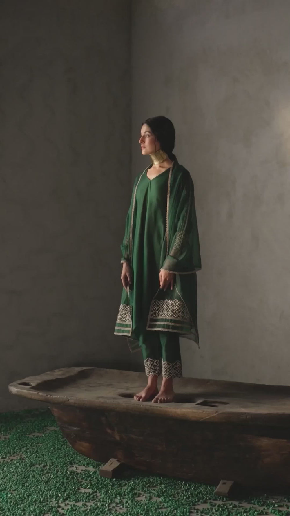 A forest green, silk-chanderi set featuring an asymmetric kurta with zari & gota embroidery on the sleeves. It is paired with straight pants with matching embroidery at the hem.