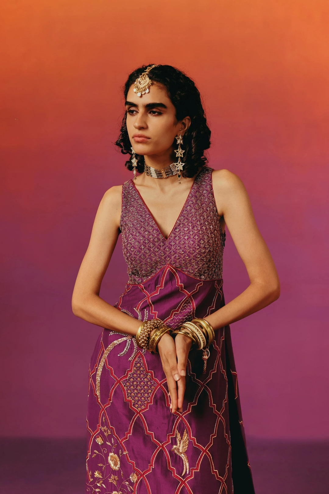 Close-up of the beaded bodice of Warra's wine-purple kurta set with a diamond pattern, worn with a gold mathapatti headpiece, choker and layered bangles