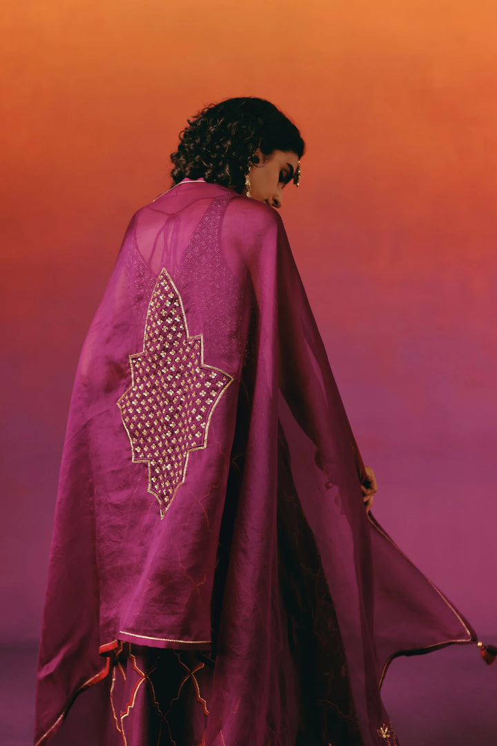 Back view of a model in Warra's wine-purple kurta set with the matching dupatta draped cape-like over the shoulders, showing a gold sequin star motif