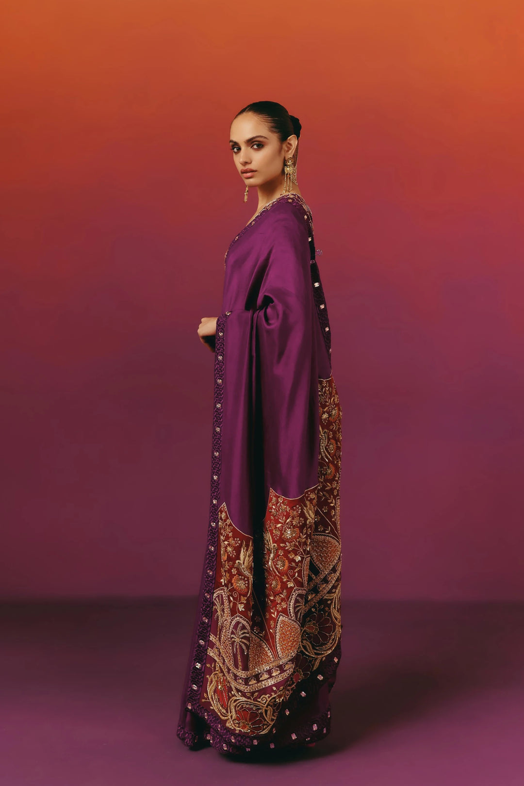Side profile of a model in Warra's purple silk saree showing the pallu draped over the shoulder with a rust-red hand-embroidered border of palm trees and florals