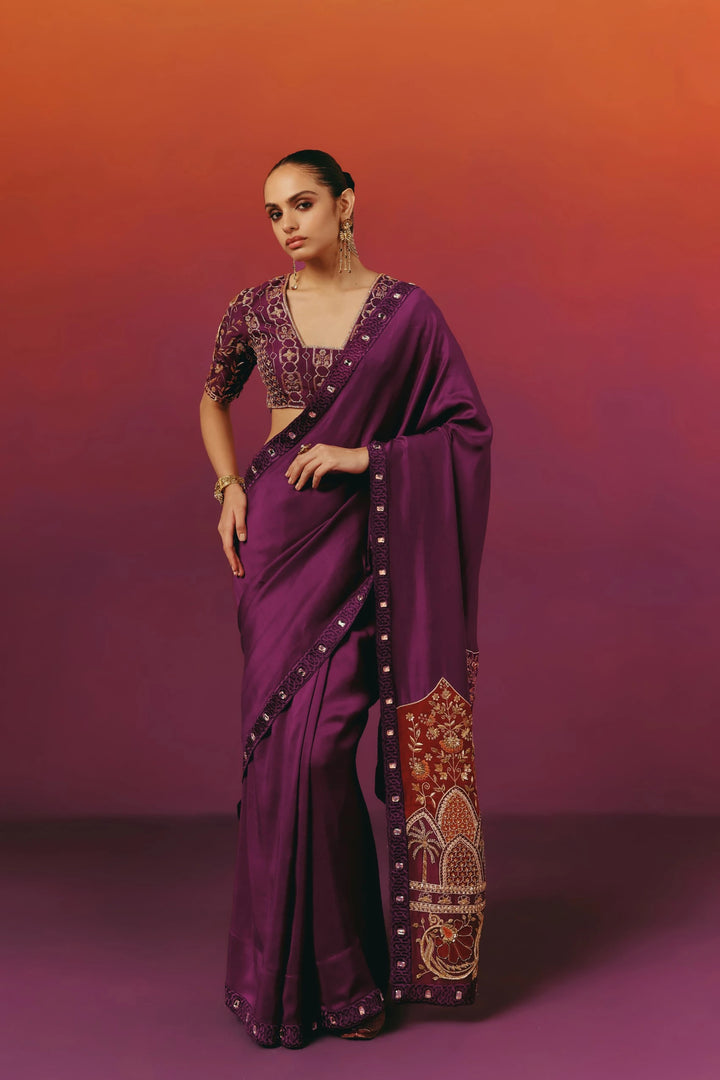 Full-length front view of a model in Warra's purple silk saree with a hand-embroidered peacock-and-floral blouse and a rust-red embroidered pallu border with palm tree motifs