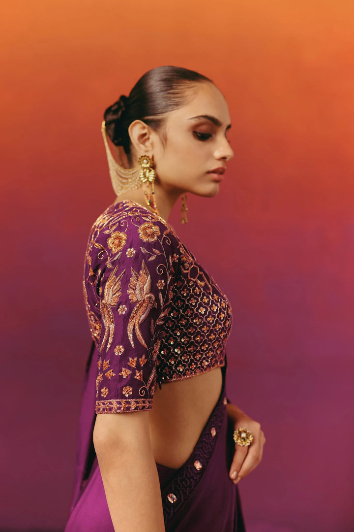 Close-up side view of Warra's purple silk saree blouse showing hand-embroidered bird and floral motifs in gold and copper thread on the sleeve and bodice