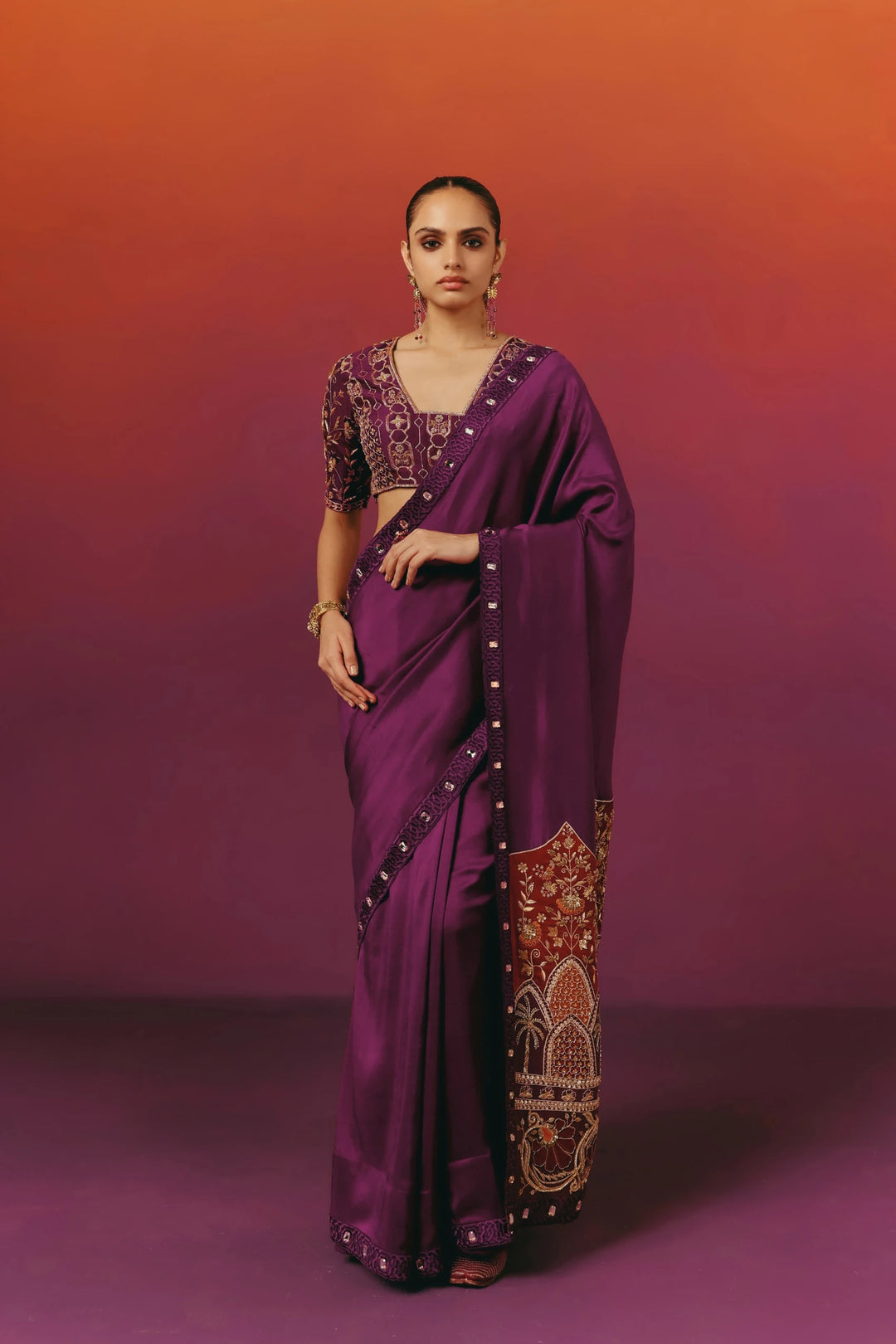 Front view of a model in Warra's purple silk saree with an embroidered V-neck blouse, statement drop earrings and a gold cuff bracelet