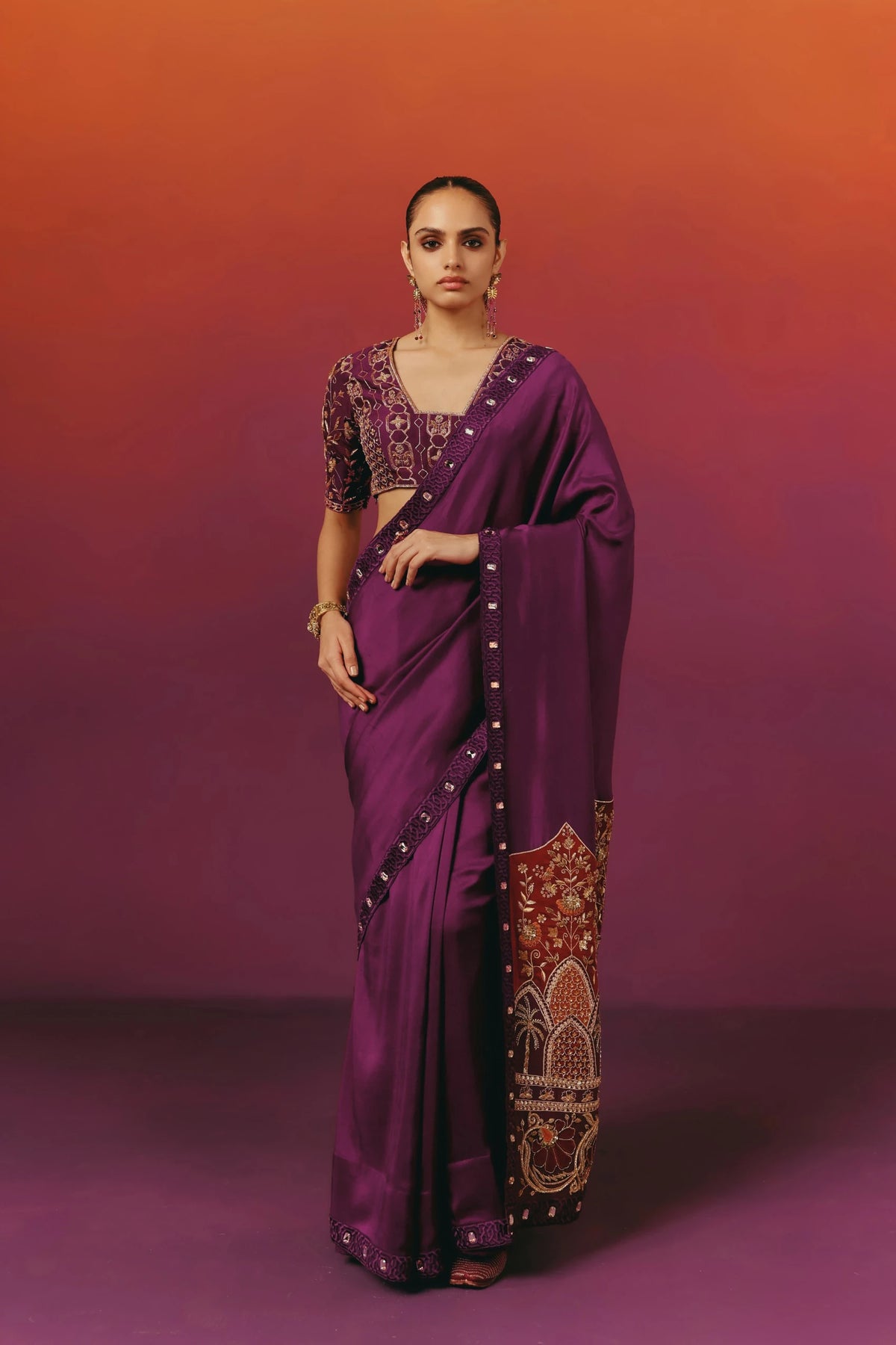 Front view of a model in Warra's purple silk saree with an embroidered V-neck blouse, statement drop earrings and a gold cuff bracelet