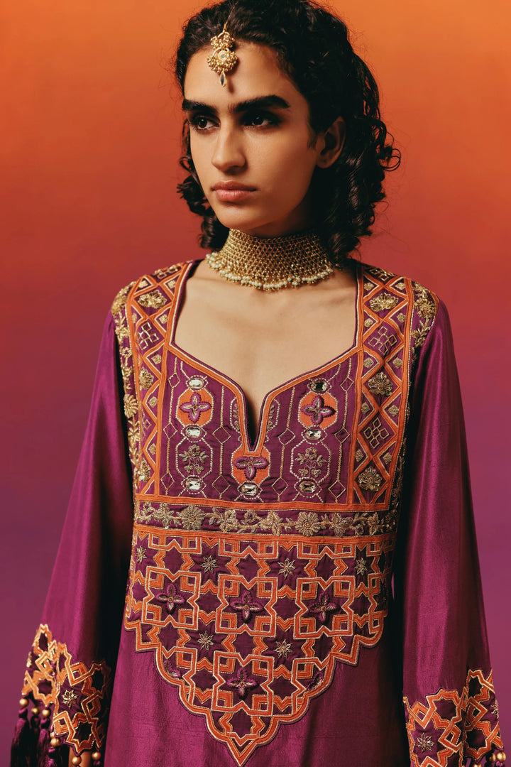 Close-up of a model in Warra's magenta silk kaftan with an orange-and-gold star-and-diamond embroidered yoke, paired with a maang tikka headpiece and layered choker