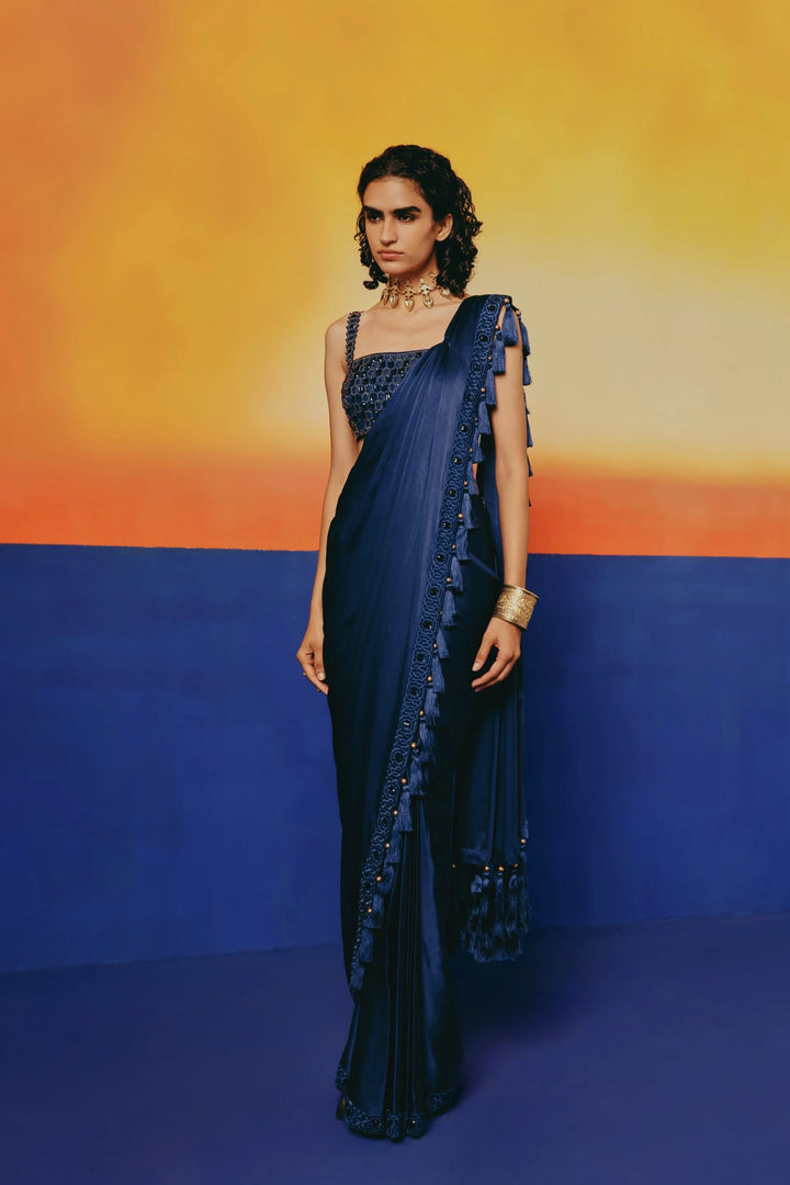 Front view of a model in Warra's Crystal Blue Tassel Saree with the crystal-bordered, tasseled pallu draped over one shoulder and a gold cuff bracelet