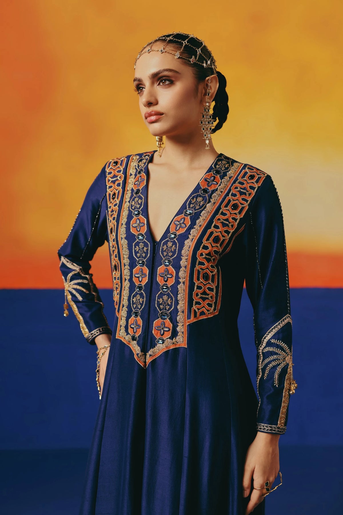 Close-up of the embroidered yoke on Warra's navy silk anarkali showing an orange-and-navy geometric trellis pattern with jewelled buttons down the front