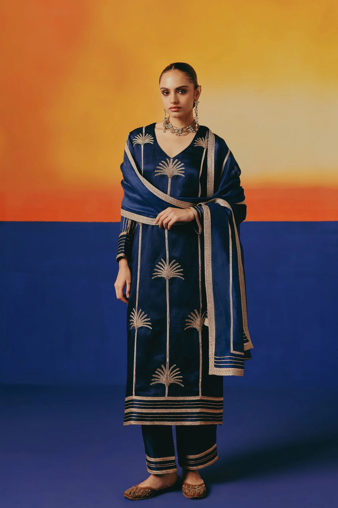 Full length view of a straight kurta set with palm tree embroidery with dabka and sequins with matching pants and dupatta.