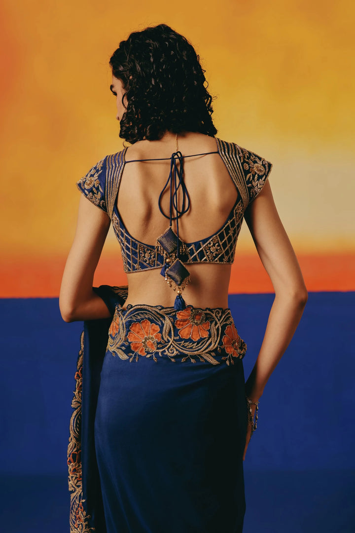 Close-up back view of Warra's navy backless blouse with a lattice pattern and an orange floral embroidered waistband on the saree