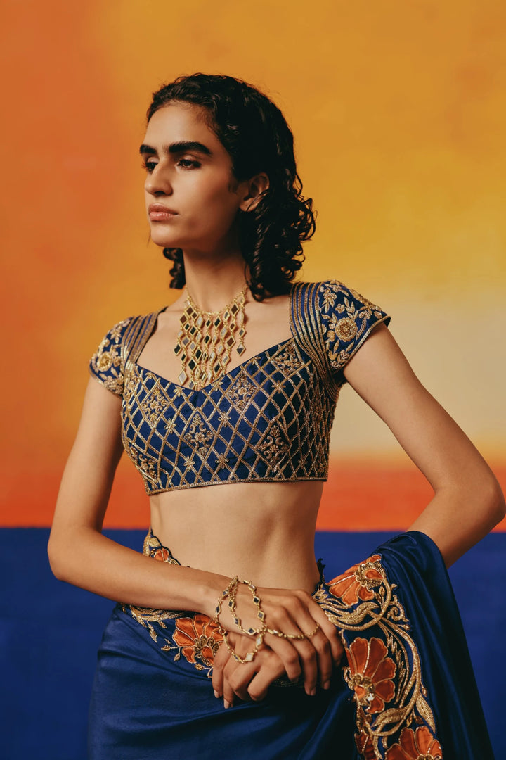 Close-up of a model wearing Warra's navy saree blouse with gold lattice embroidery, mirror-work jewellery and layered bangles