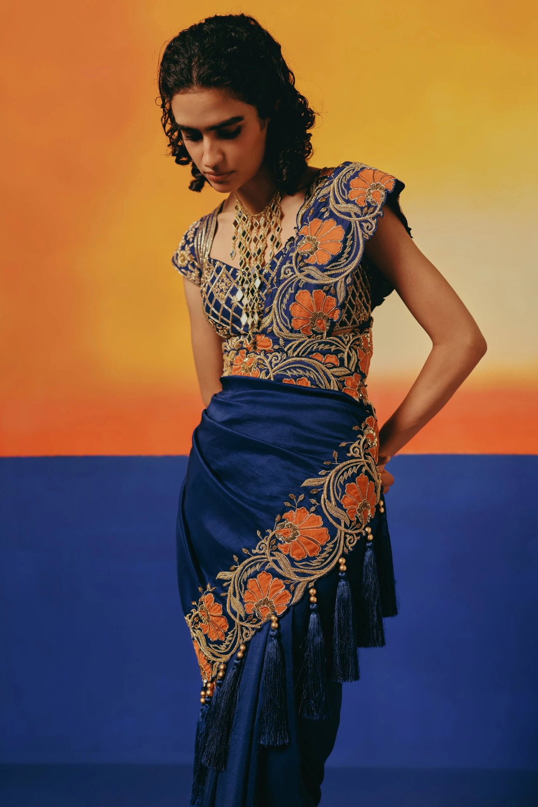 Close-up of Warra's navy saree blouse and drape with orange floral embroidery, paired with a matching embroidered potli bag