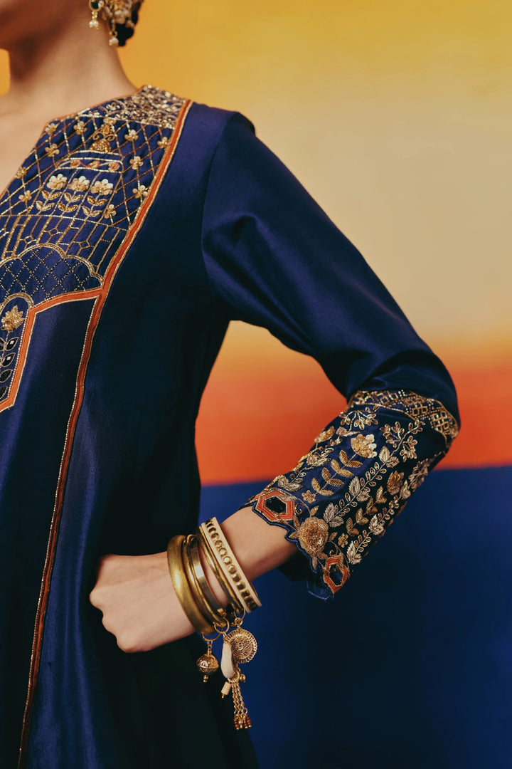 Close-up of the sleeve cuff on Warra's navy silk tunic showing gold floral embroidery and layered bangles