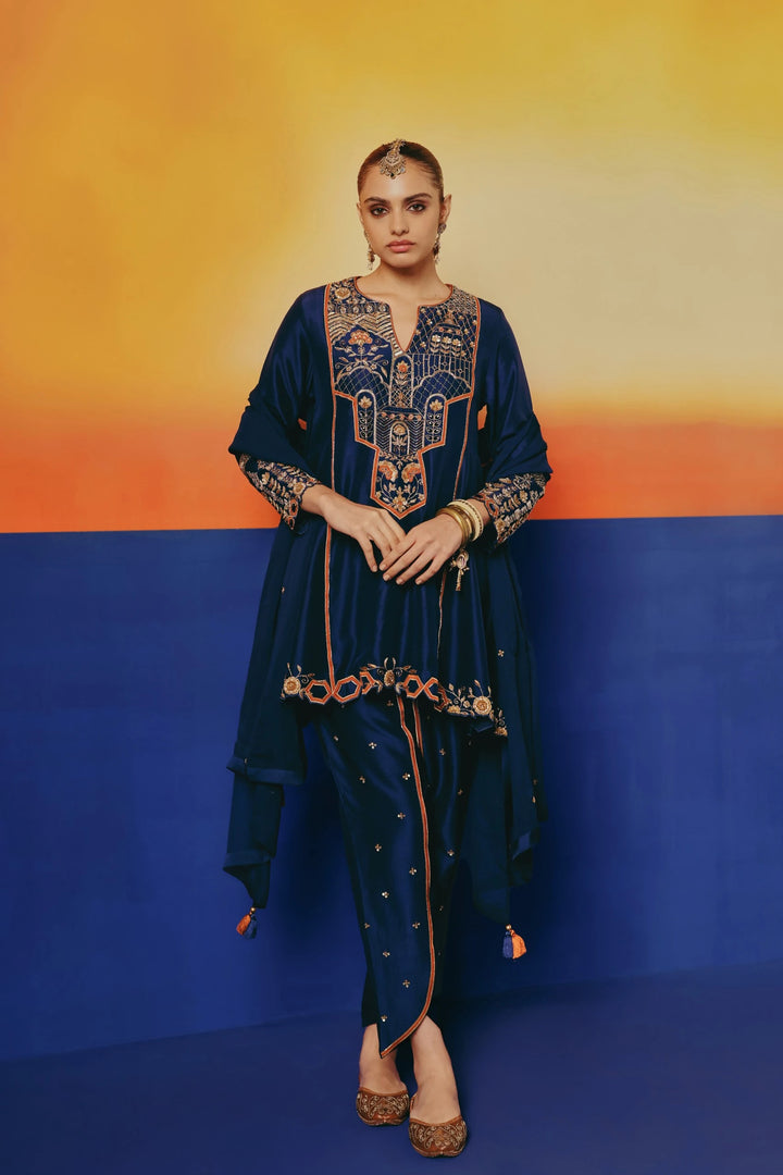 Full-length view of a model walking in Warra's navy silk tunic with ornate gold embroidered yoke, dhoti-style pants and a dupatta