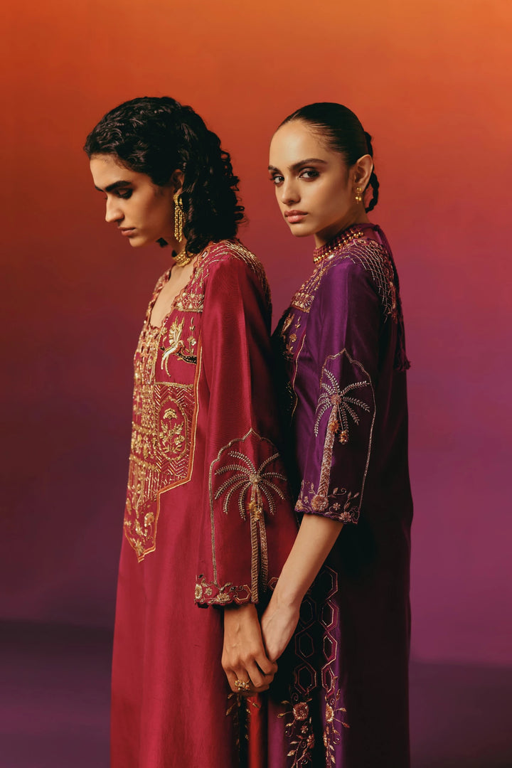Back view of a model in Warra's deep red silk kaftan from the red-and-purple pairing, showing gold floral embroidered yoke and matching embroidered cuffs and hem border