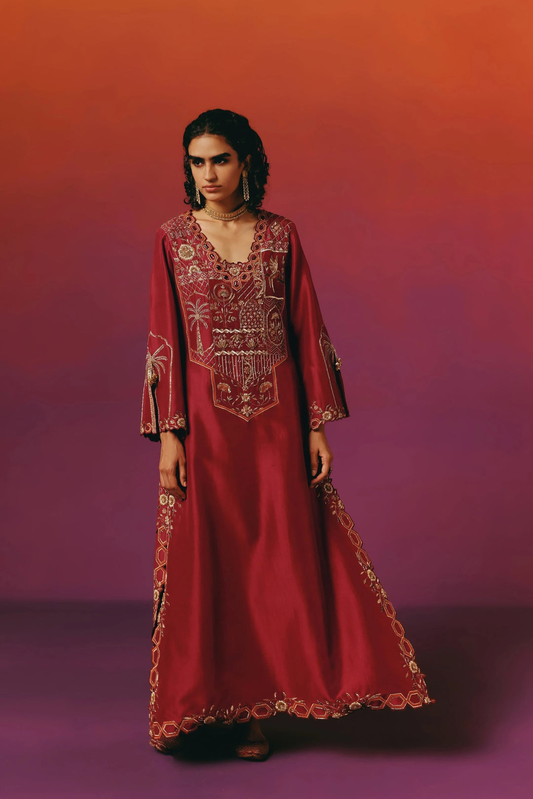 Full-length front view of Warra's deep red silk kaftan with dense gold floral embroidery on the bodice and neckline, standing with hands relaxed at her sides