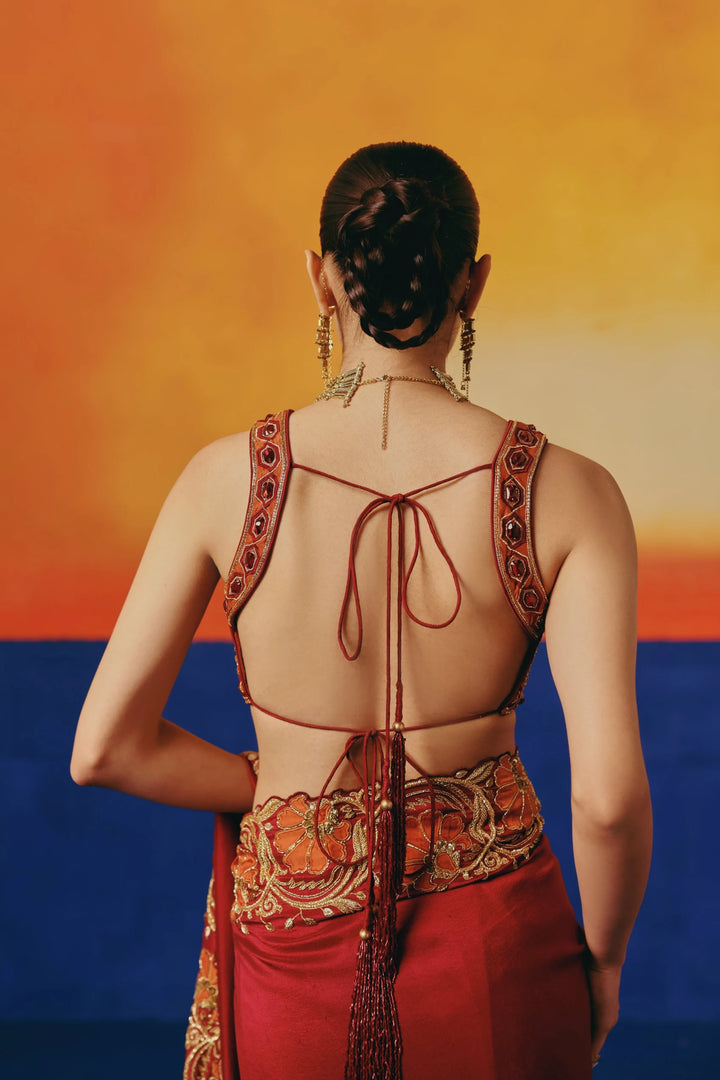 Back view of a model in Warra's red silk saree showing the tie-back blouse detail and orange floral embroidered waistband