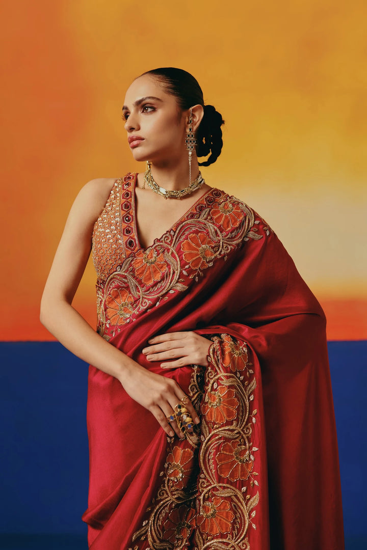 Close-up of a model in Warra's red silk saree showing the orange floral embroidered pallu and a jewelled one-shoulder blouse