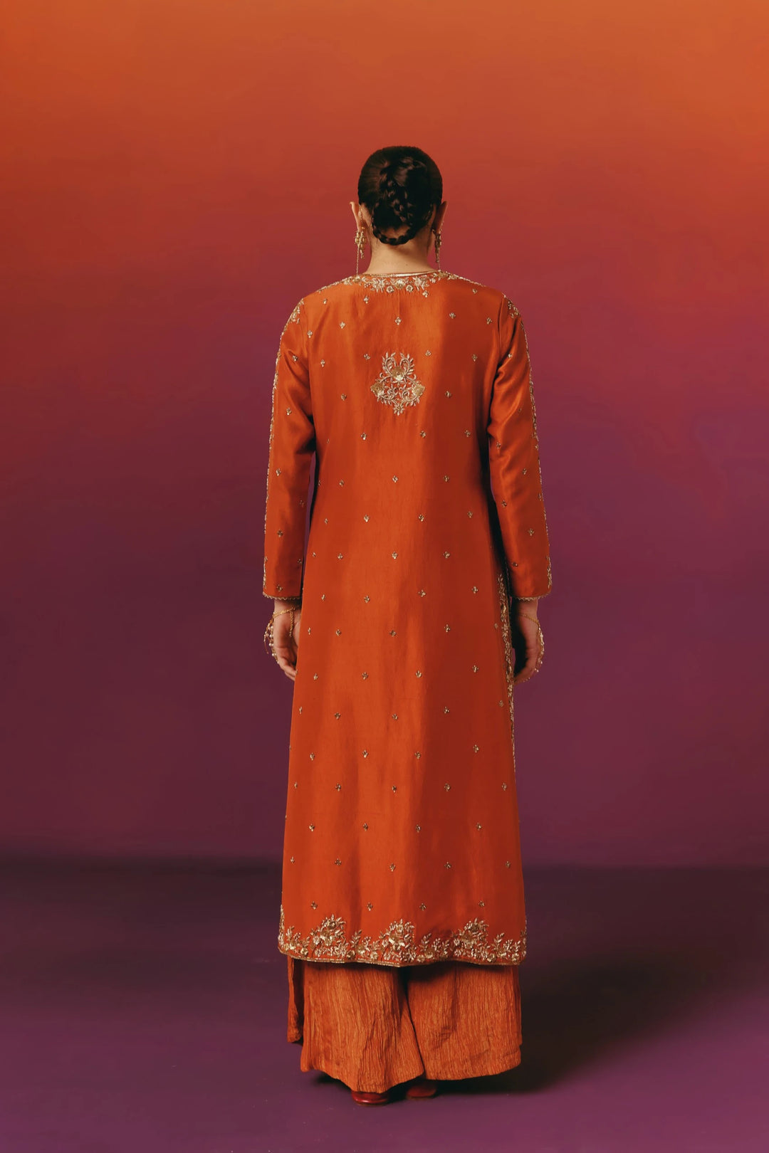 Back view of Warra's rust-orange silk kurta showing a gold floral medallion motif below the neckline and an all-over booti pattern with an embroidered hem border